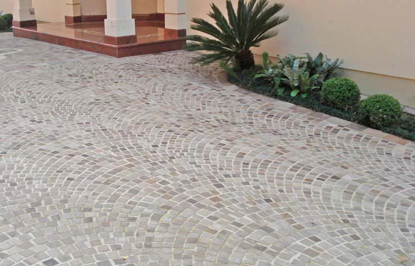 House entrance paved with Vulcano stone laid in arches, beside a planted bed