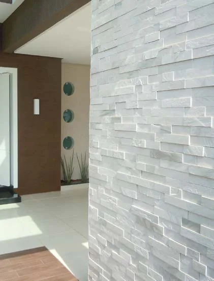 Wall clad in white quartzite stacked stone next to a wooden door