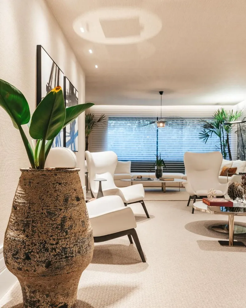Maceta alta de arcilla moteada con una planta frondosa en una sala luminosa