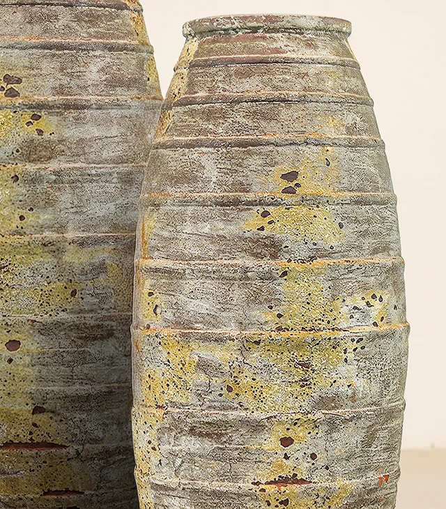 Close-up of two tall Signature vases: raised rings and a yellow, green and gray mineral patina